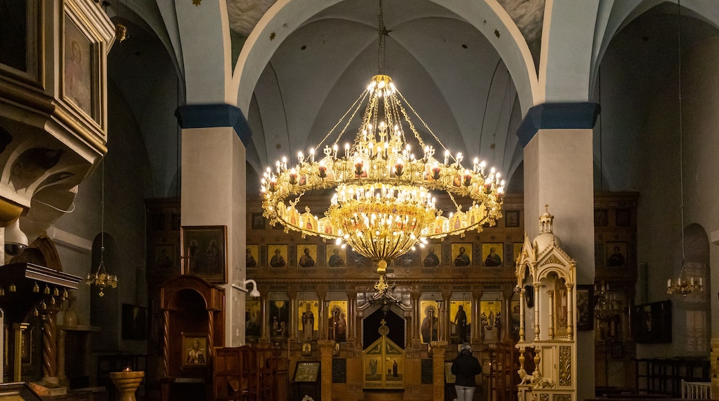 An ornate church interior with a large chandelier, arched ceilings, and religious icons.