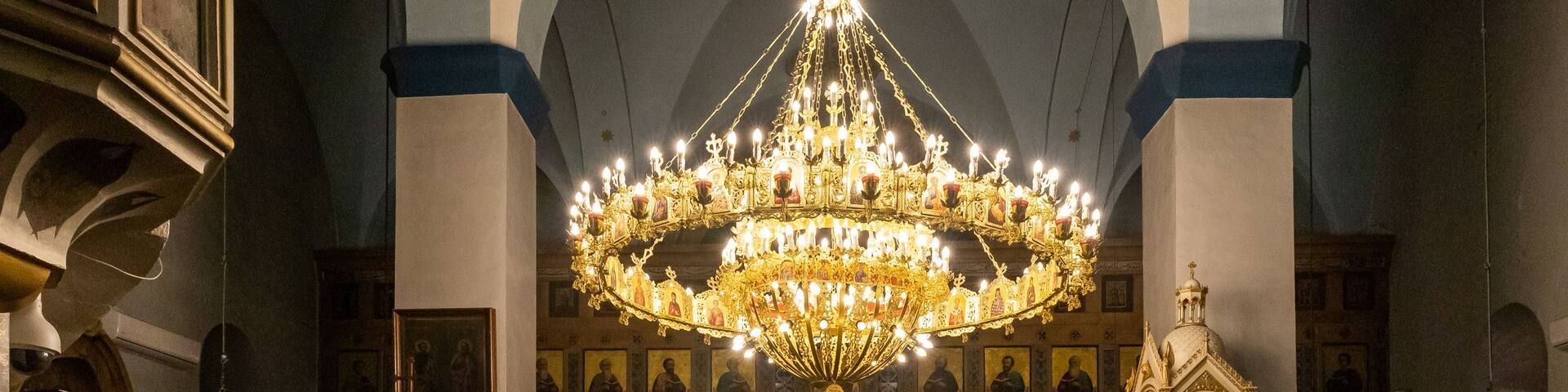 An ornate church interior with a large chandelier, arched ceilings, and religious icons.