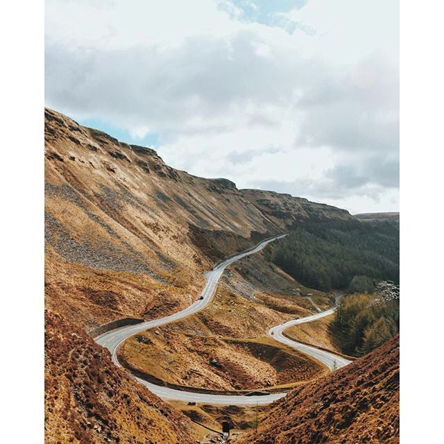 A winding road through a hilly landscape with sparse vegetation.