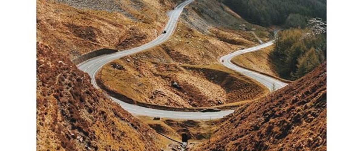 A winding road through a hilly landscape with sparse vegetation.