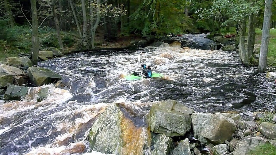 Heading into the second main drop, River Washburn. There are a lot of fast rapids, tight breakouts and small drops on the Washburn, used by canoeists on scheduled dam releases, which put water down this small river at a level equivalent to a natural spate. This weir and the following drop are the biggest, and experienced paddlers tend to break out of the main flow between the two, often to play on the stopper wave of the first drop. This paddler has just broken back in from the eddy on the right of the photo and is turning to run down the centre of the chute of the second drop, which has a big wave train, but no playable wave. This is the spot where 'Jim' hits the water in the Rosemary & Thyme tv episode "The Memory of Water" (2004).
