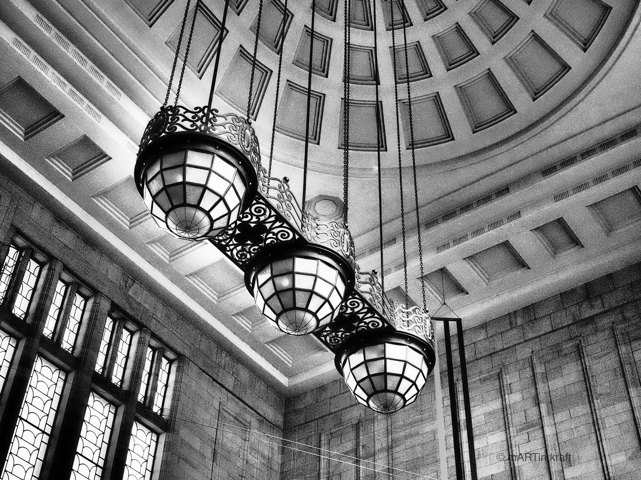 A grand interior with ornate hanging lamps and a domed ceiling.