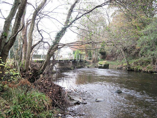 A river flowing under a bridge surrounded by trees and vegetation.