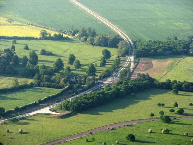 Guided busway at Oakington from a hot-air balloon, near to Westwick, Cambridgeshire, Great Britain. The concrete blocks of the hugely controversial, vastly over-budget and still-unopened Cambridge to St Ives guided busway snake across the fens, occupying the trackbed of the former railway. In the centre of the picture it is crossed by the Oakington-Cottenham road, where Oakington railway station once stood.