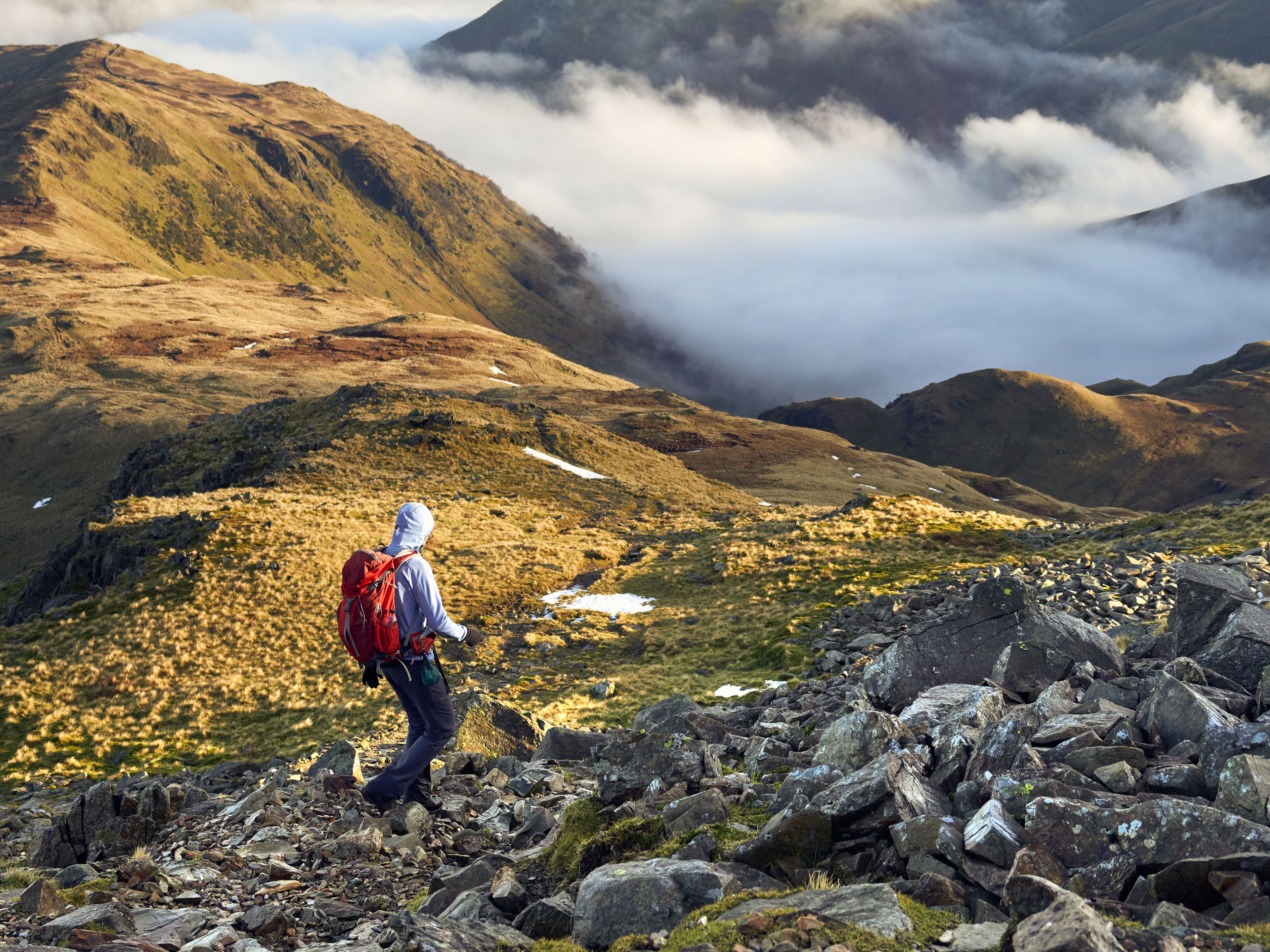 A hiker descending Hart Crag towards Hartsop Above How near Patterdale in the English Lake District.