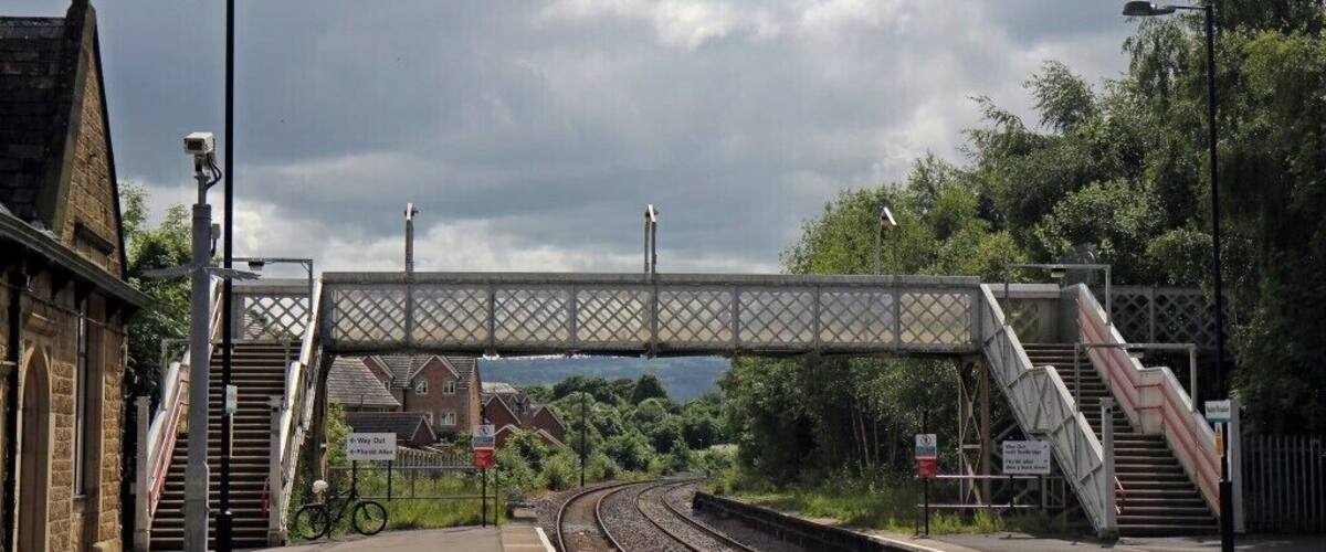 A railway station with a pedestrian bridge, tracks, and a bicycle.