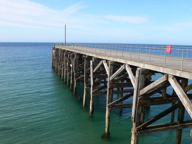 Un muelle de madera que se extiende sobre un mar tranquilo, sostenido por pilares robustos.