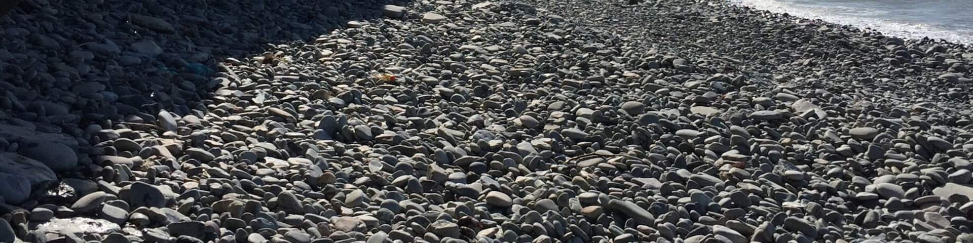 A rocky beach with ice formations and a clear sky.