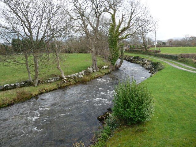 A river flowing through a rural landscape with stone walls and trees.