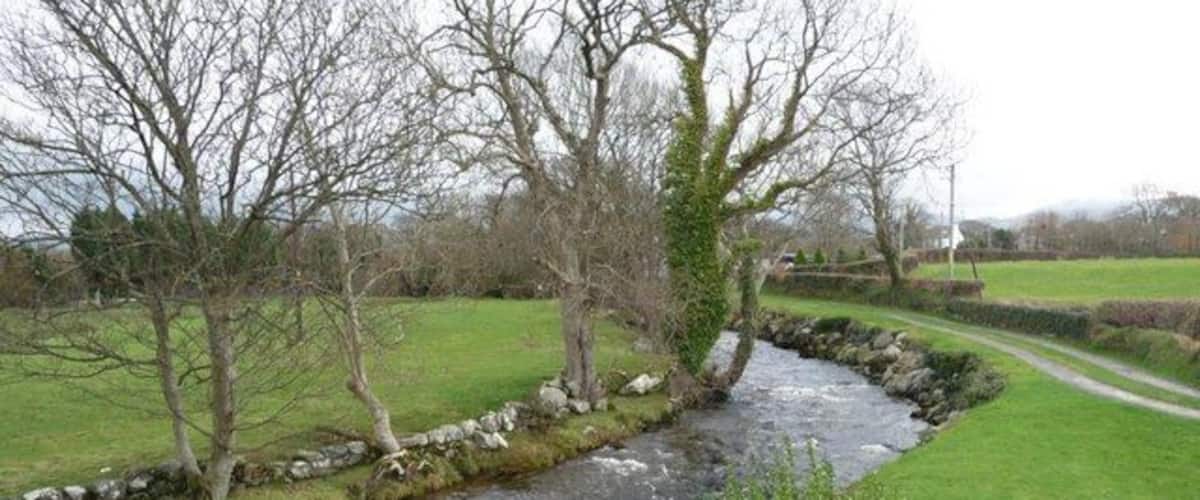 A river flowing through a rural landscape with stone walls and trees.
