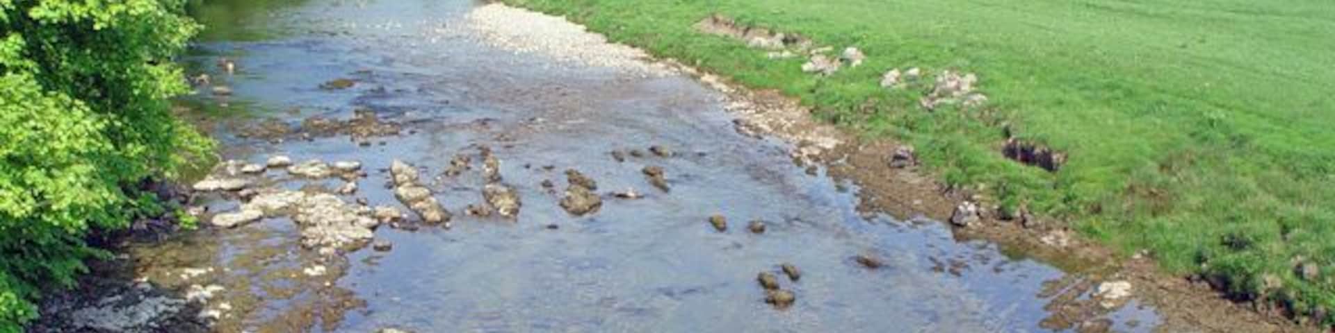 River Wharfe from the Grassington Bridge, Grassington, North Yorkshire. Looking northwest. The eastern bank of the river Wharfe carries the Dales Way long distance footpath at this point. On the skyline is Grass Wood.