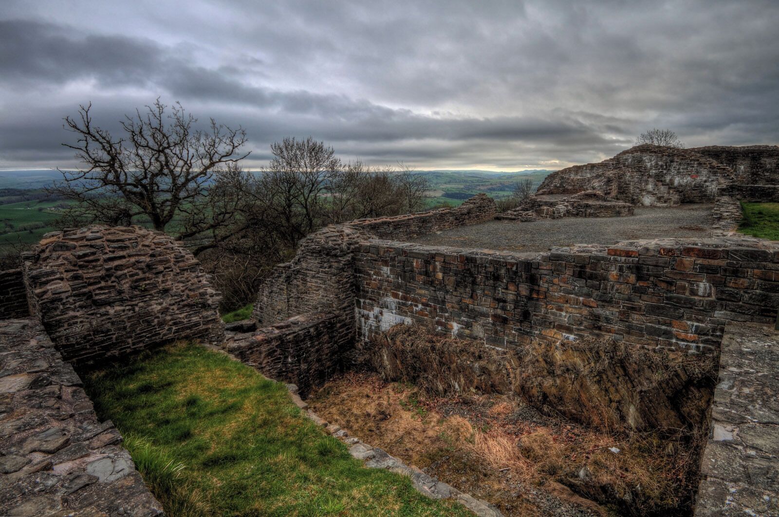 An ancient stone fortification with crumbling walls and a grassy foreground.