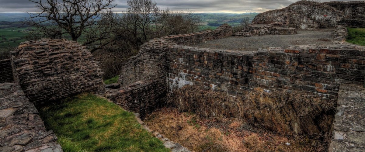 An ancient stone fortification with crumbling walls and a grassy foreground.