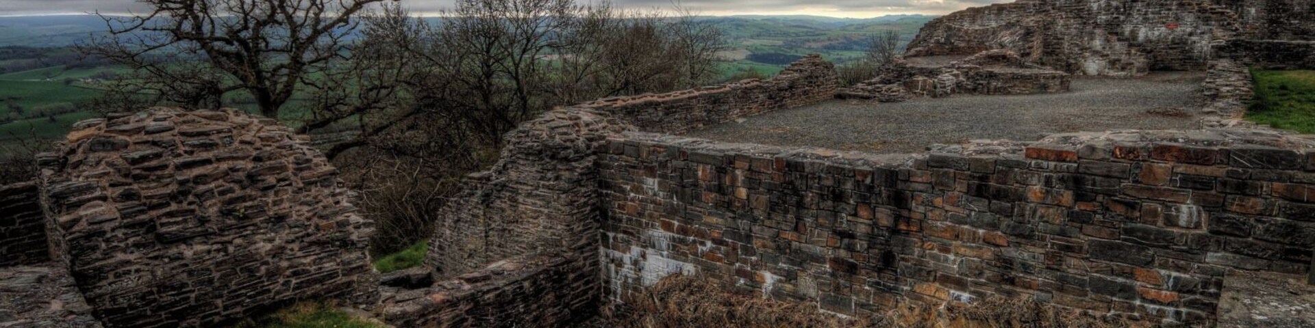 An ancient stone fortification with crumbling walls and a grassy foreground.