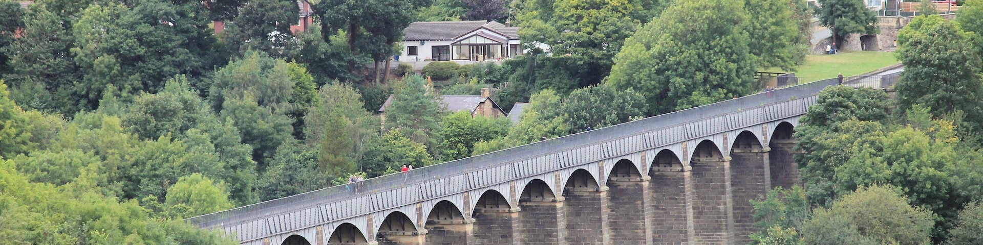 A viaduct over a river with houses in the background.