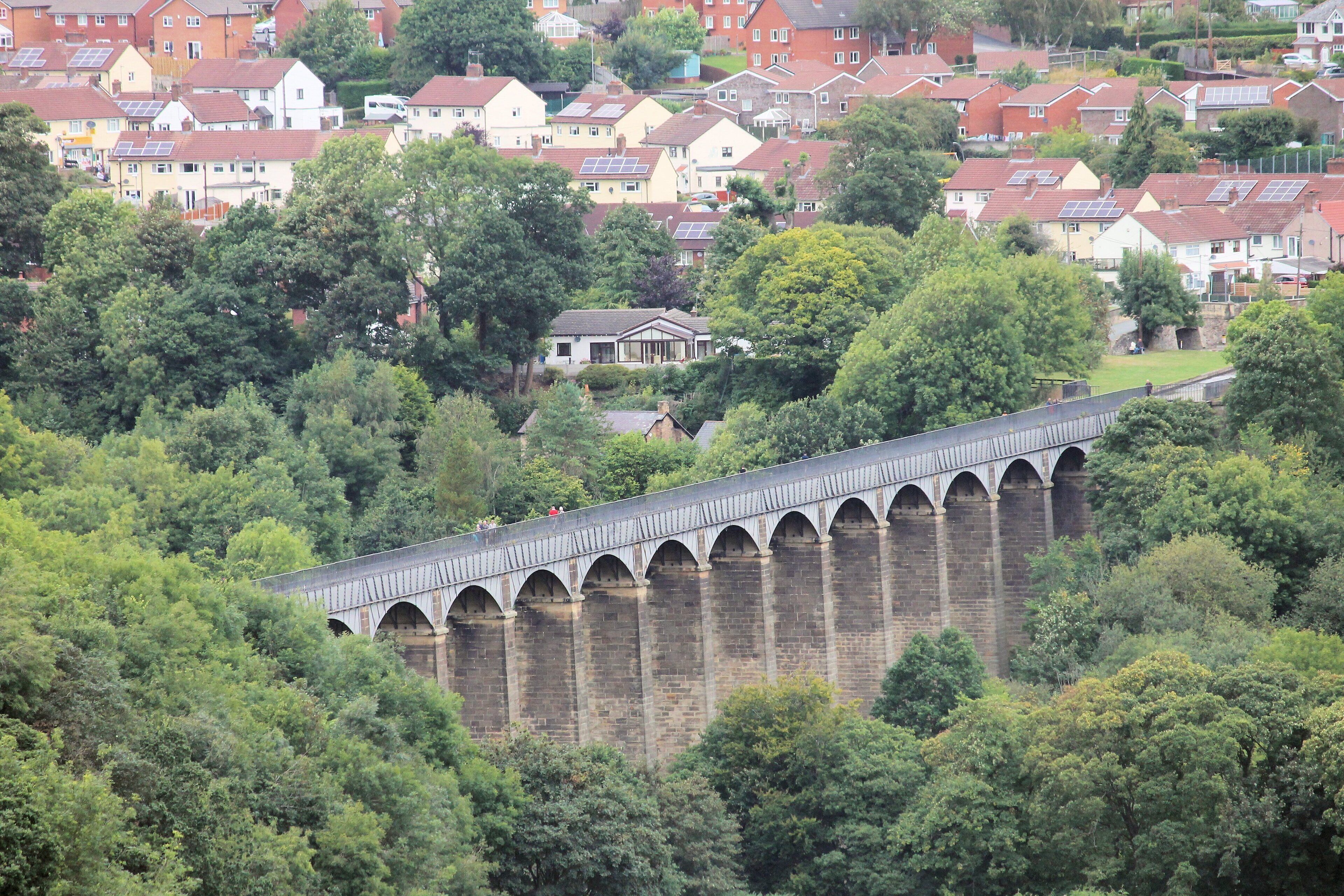 A viaduct over a river with houses in the background.