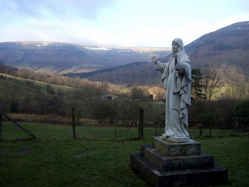 'Our Lady of Llanthony' The statue stands in front of the C19 monastery built by Father Ignatius and his monks and marks the vision of the Virgin Mary believed to have been seen by several of them near this spot in 1880. The view is across the Vale of Ewyas towards the most easterly ridge of the Black Mountains that marks the border between Wales and England.