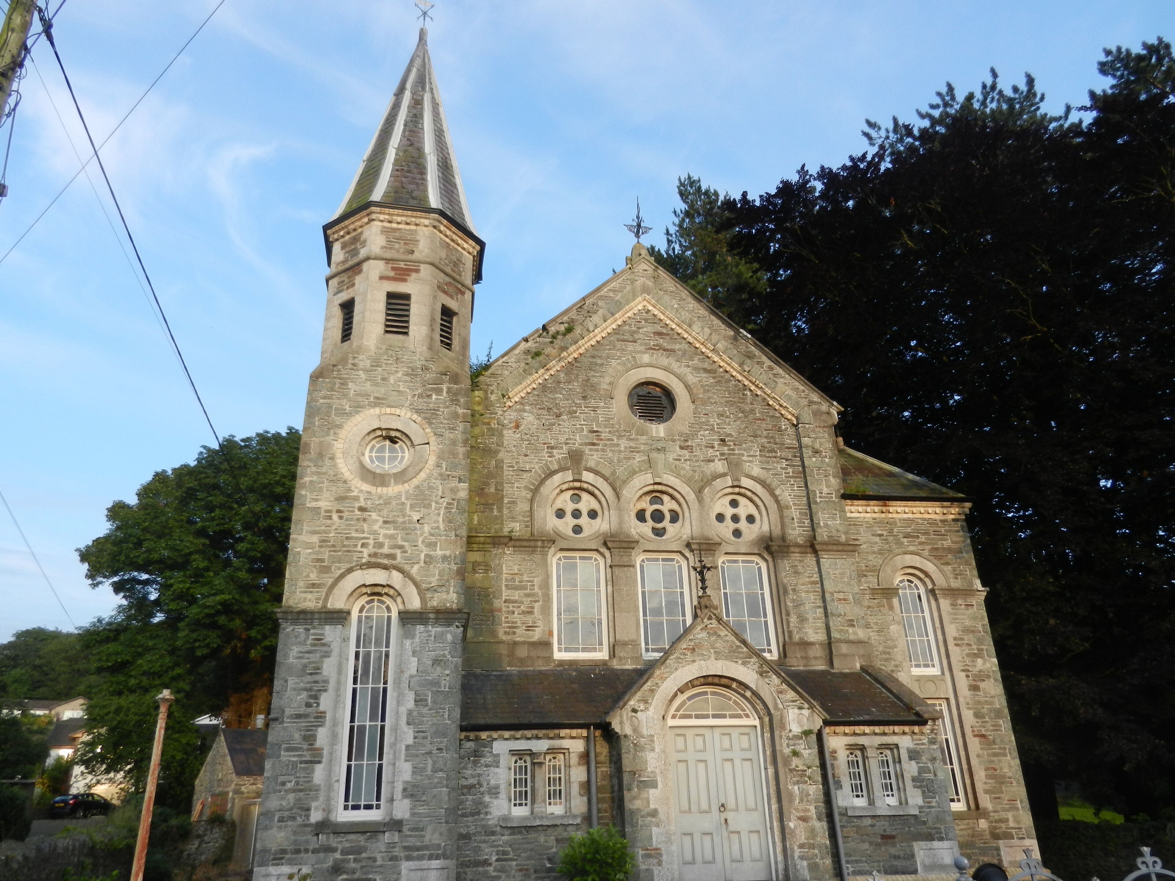 A stone church with a tall tower and a pointed roof.