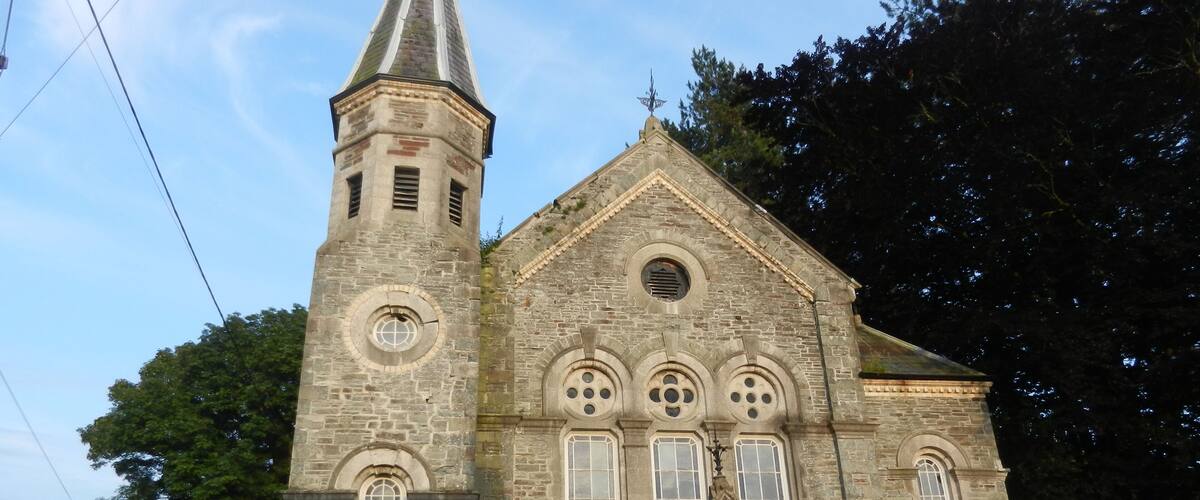 A stone church with a tall tower and a pointed roof.