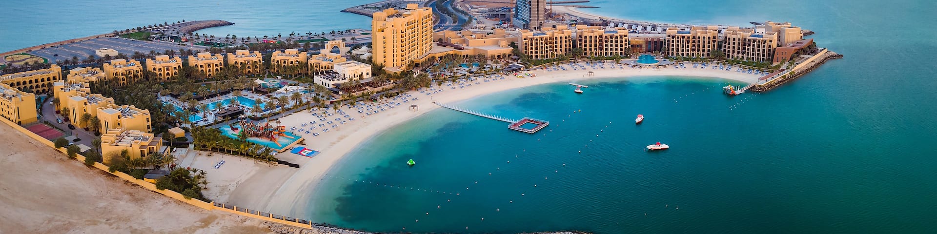 A coastal resort with a beach, swimming pools, and a marina.