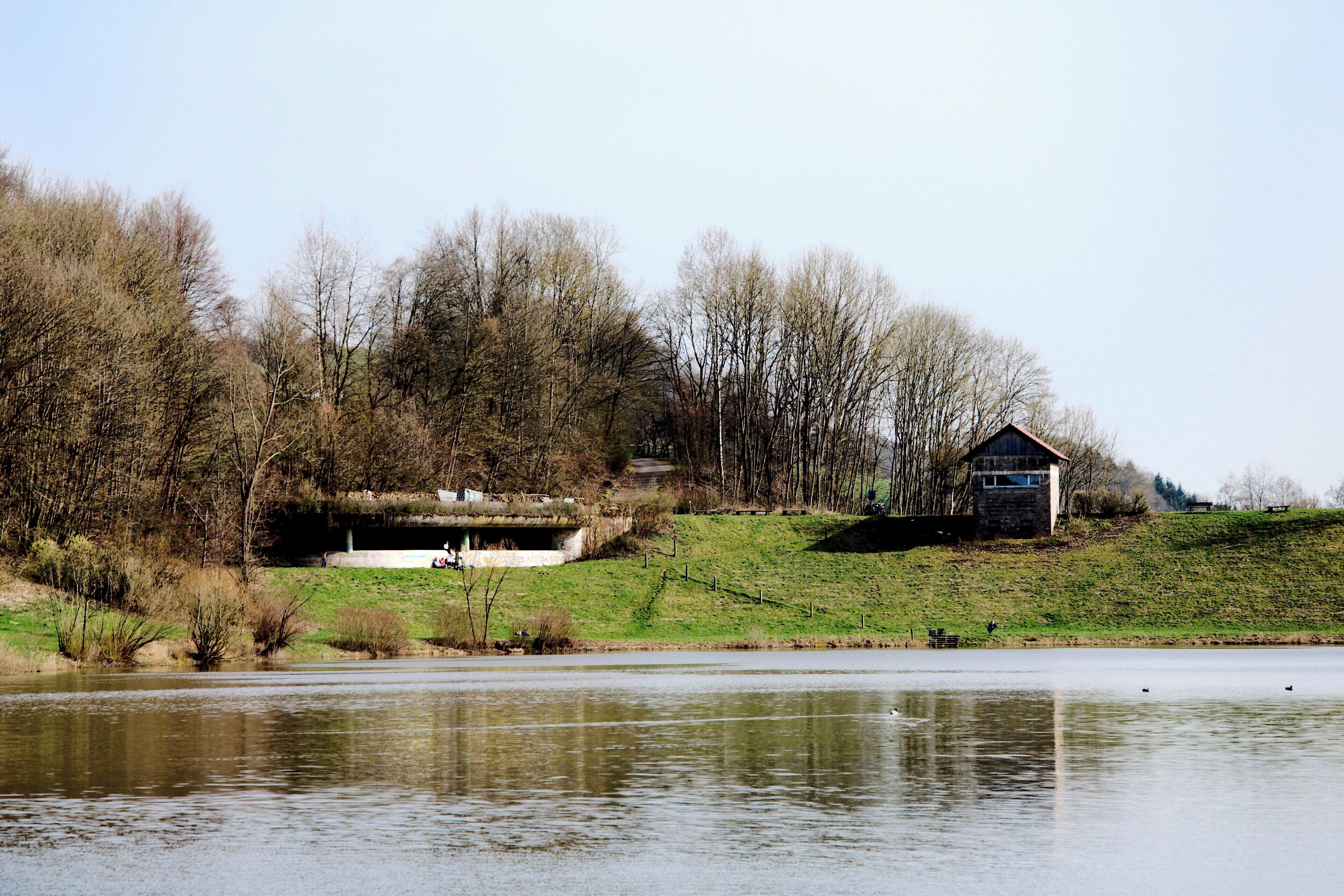Hochwasserrückhaltebecken Gnadental: Blick über den Stausee auf den Staudamm. Links die Hochwasserentlastungsanlage, rechts das Betriebsbauwerk.