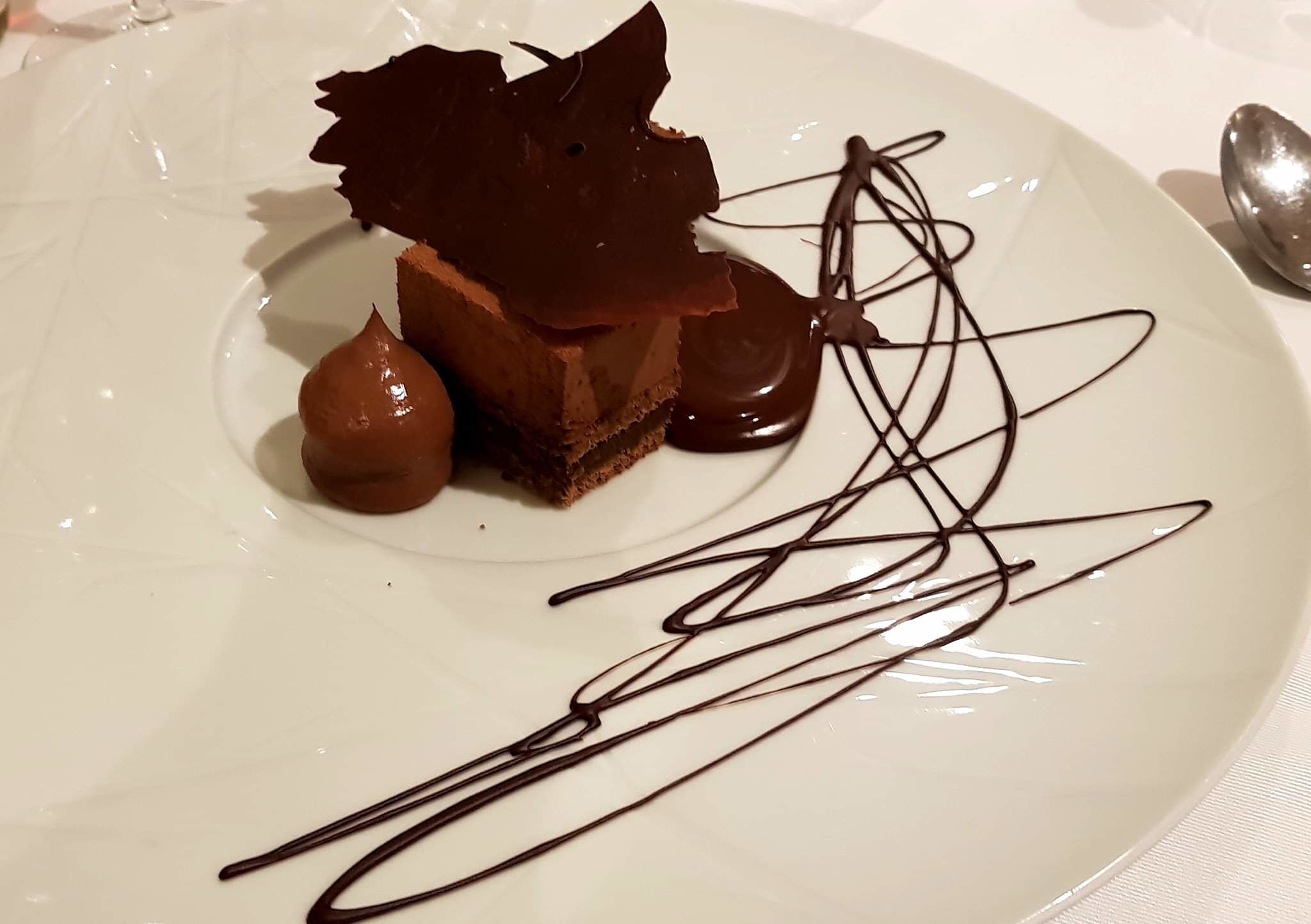 A dessert on a plate with chocolate shavings and sauce.