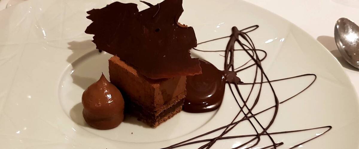A dessert on a plate with chocolate shavings and sauce.