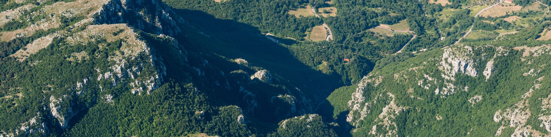 Un paisaje montañoso con un valle profundo y un río.