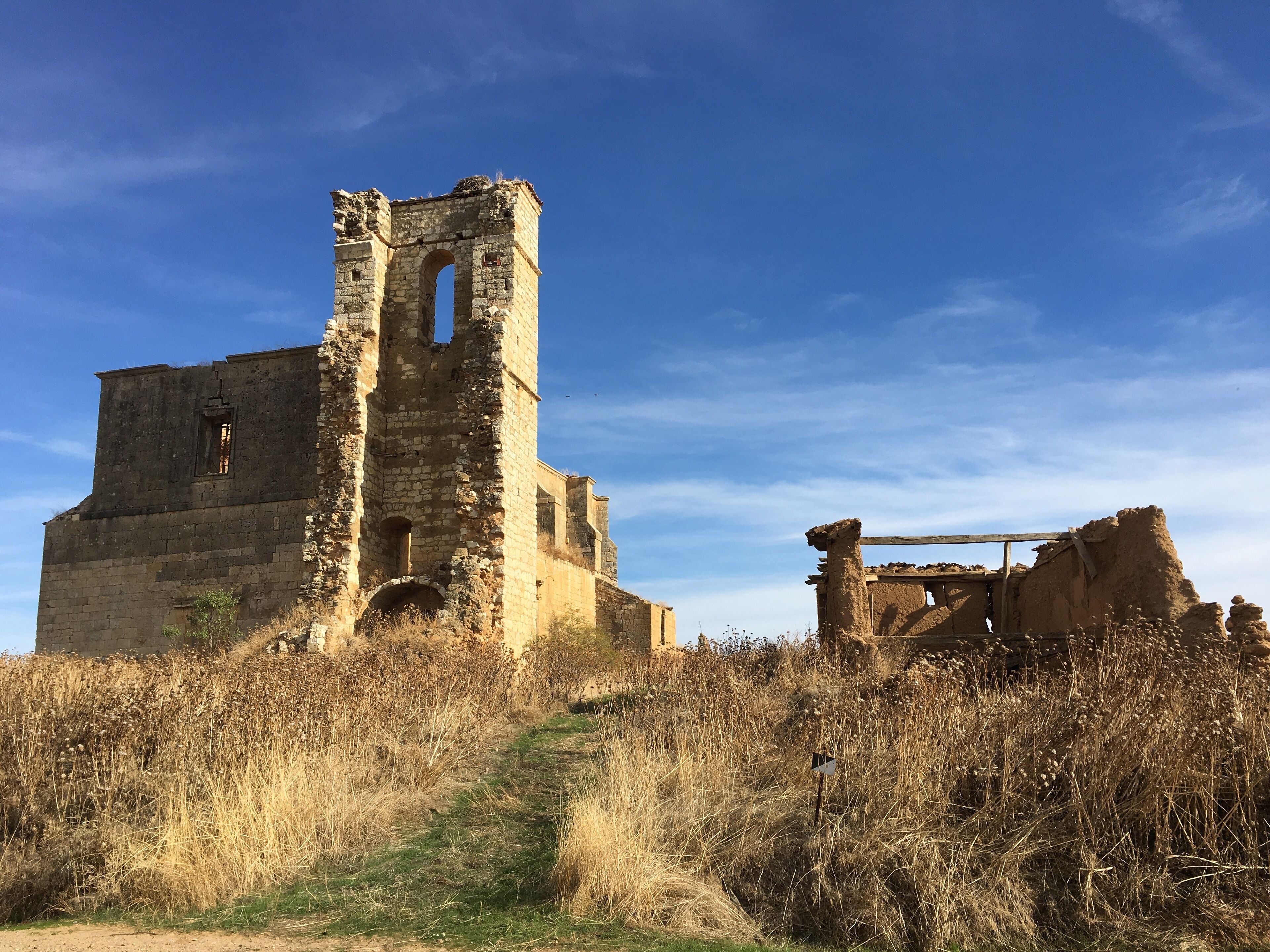 An ancient stone structure with a tall tower and a smaller ruin nearby.
