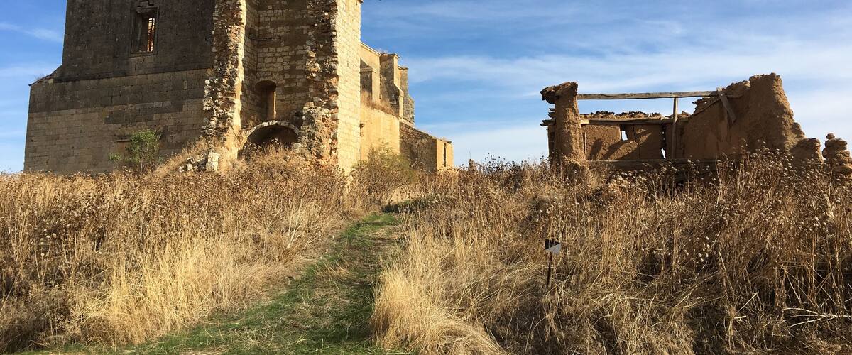 An ancient stone structure with a tall tower and a smaller ruin nearby.