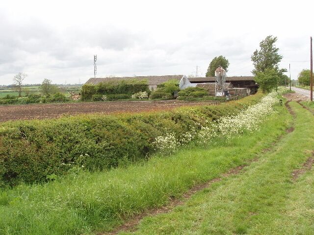 North Hill Farm The farm buildings are on the A413 main road. View from its junction with the minor road to Granborough. The field over the hedge has been ploughed recently.