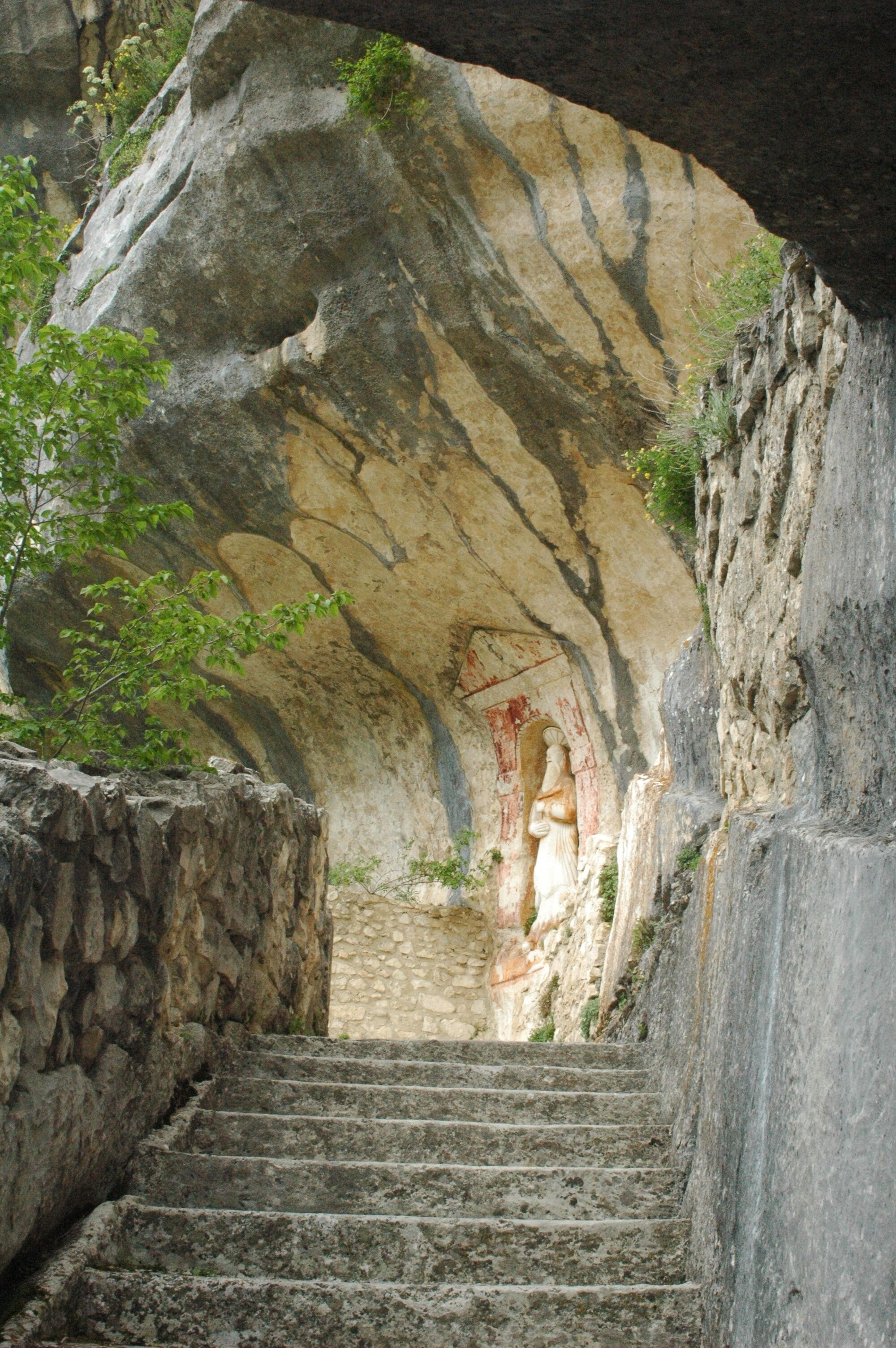 A stone staircase leading up to a cave entrance with a carved figure.
