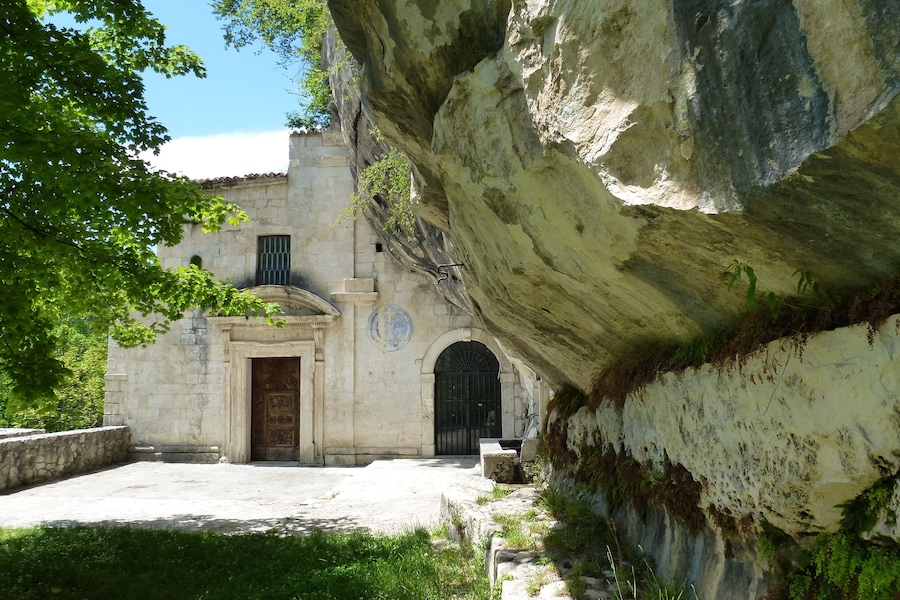 Un edificio de piedra con una gran formación rocosa a la derecha.