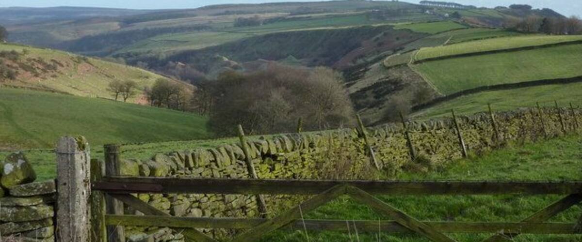 Looking east down Bretton Clough The transmitter mast on Sir William Hill, and the Barrel Inn are on the right horizon