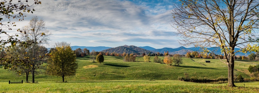 Extensive pastures of horse farm in Albemarle County, in central Virginia, with Blue Ridge Mountains in far distance and Fox Mountain center.