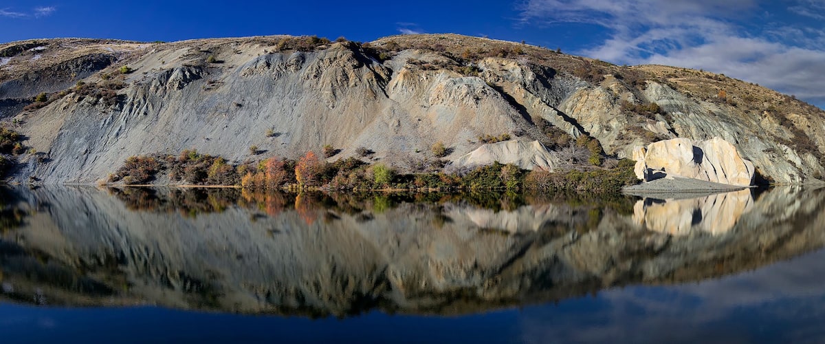 A calm lake with a rocky cliff in the background.
