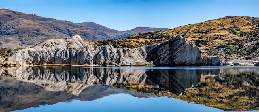 Une chaîne de montagnes dont les contours se reflètent dans un lac.