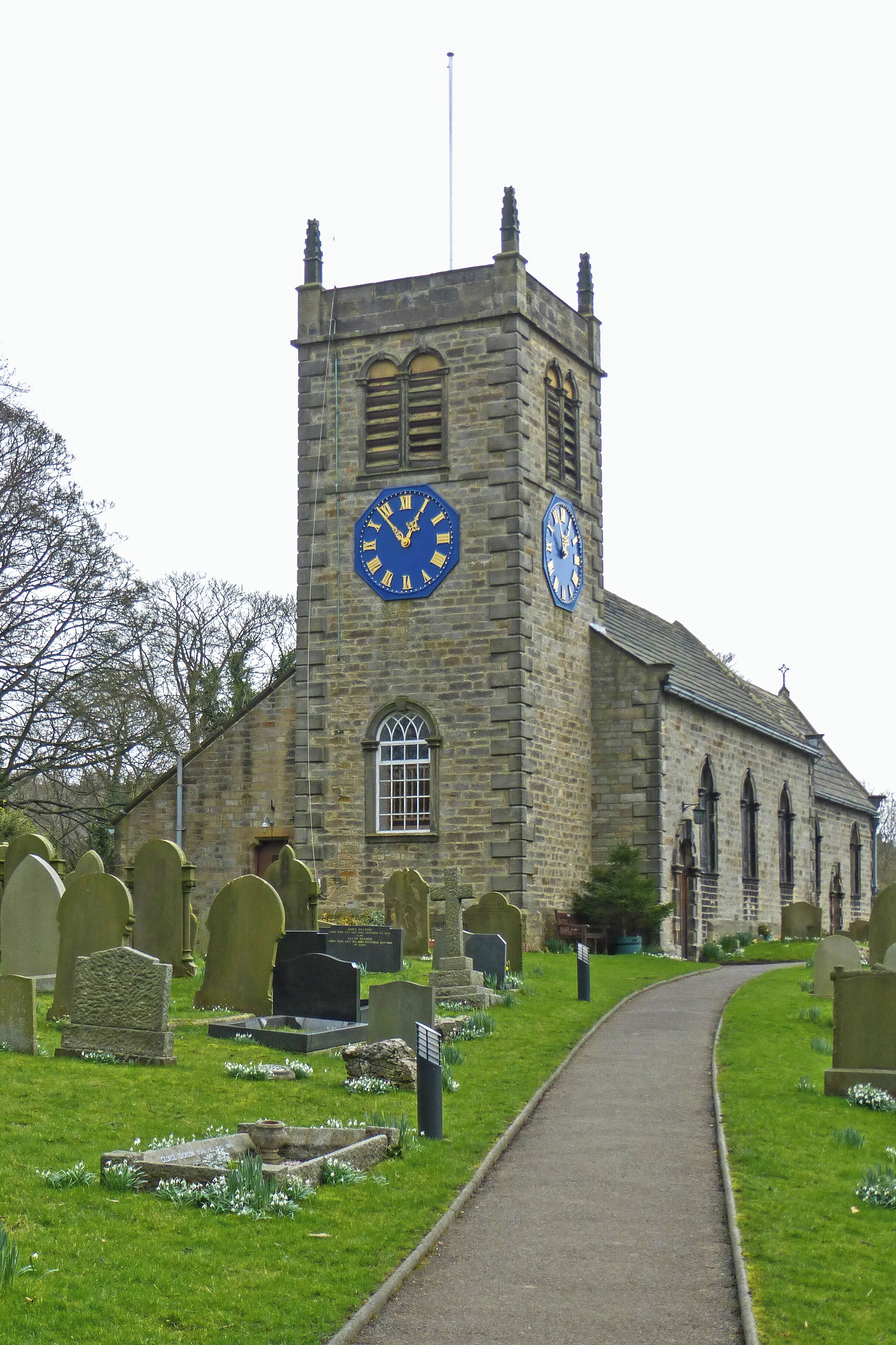A church with a clock tower and a cemetery in front.