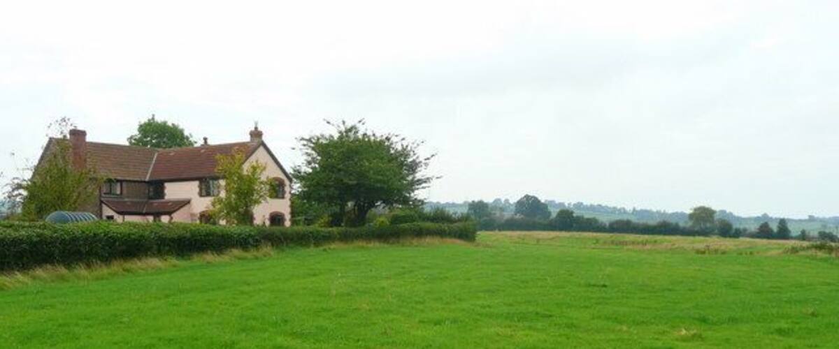 A rural landscape with a house and a large green field.
