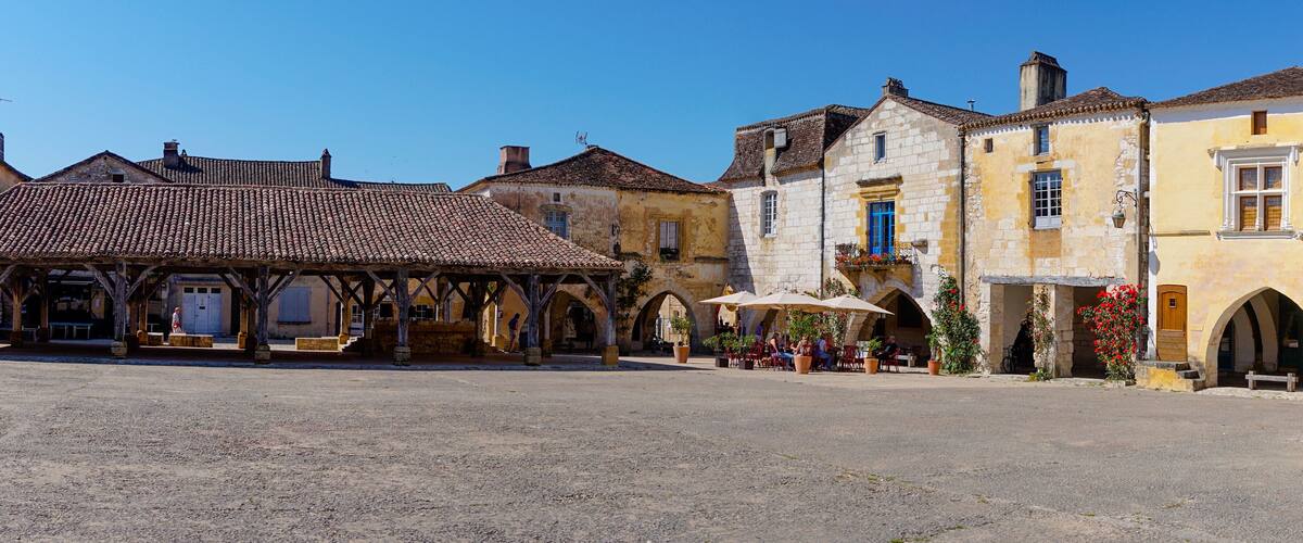 A historic square with cobblestone pavement, traditional buildings, and outdoor seating areas.