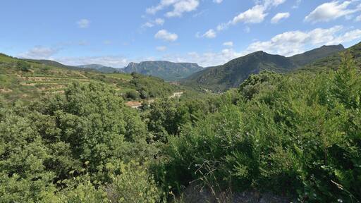 In the center, the RD177 (departemental road), the village of Vieussan and in the background the Massif du Caroux. Vieussan, Hérault, France. Haut-Languedoc Regional Natural Park.