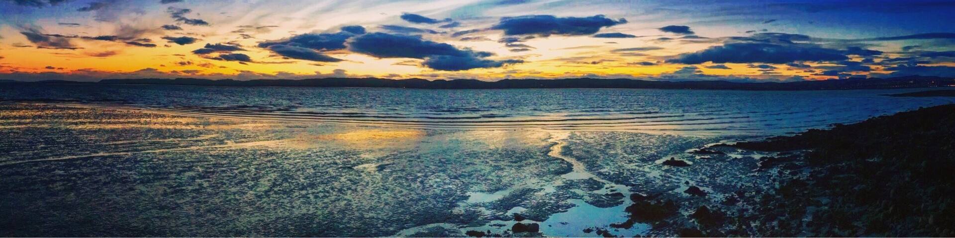 A sunset over a calm sea with a rocky shoreline.