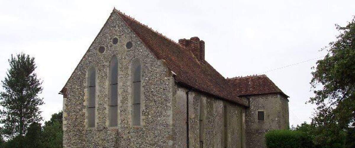 A stone church with a steep roof and large windows.