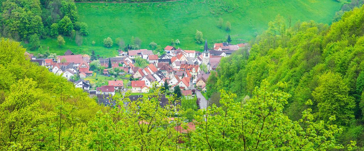 A village nestled in a valley surrounded by lush green hills.