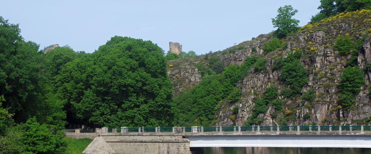 A stone bridge over a river, surrounded by lush greenery and rocky cliffs.