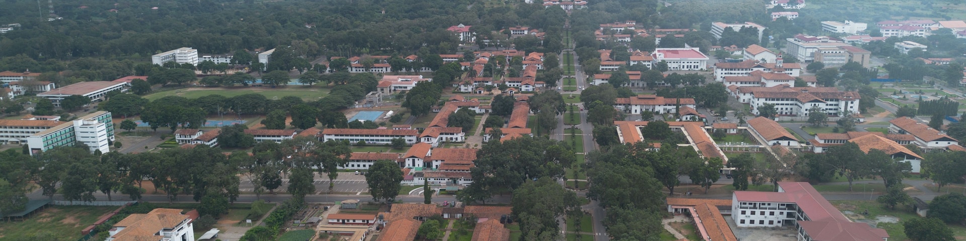 An aerial view of a city with a prominent hilltop structure, dense residential areas, and surrounding greenery.