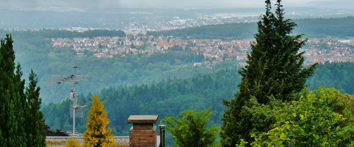 A panoramic view of a town nestled in a valley, surrounded by dense forests and hills.