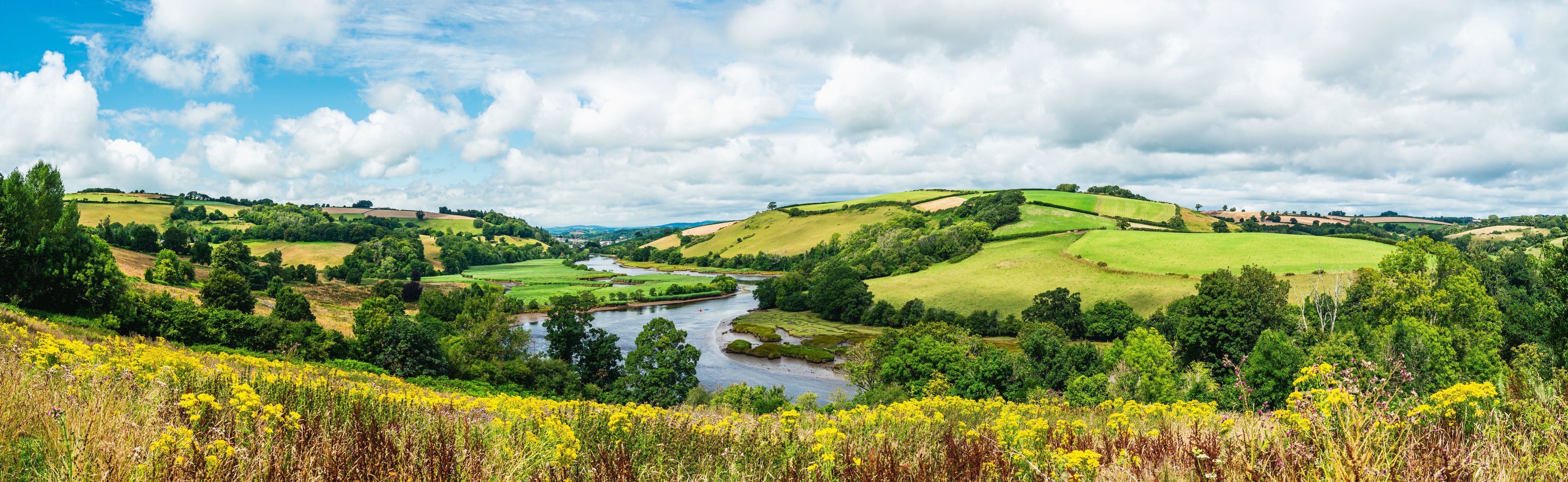 A river winding through rolling green hills with a clear sky.
