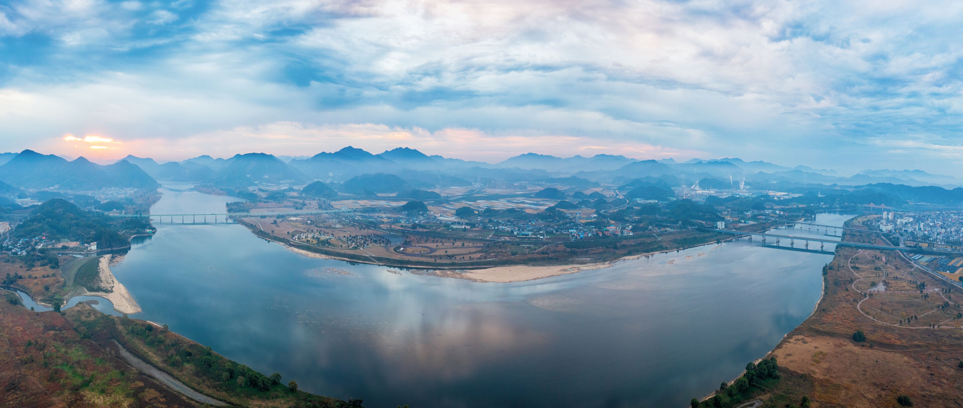A river with bridges, a town, and mountains in the background.