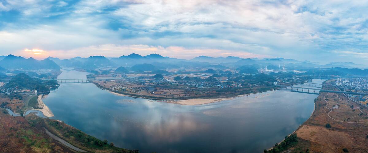 A river with bridges, a town, and mountains in the background.
